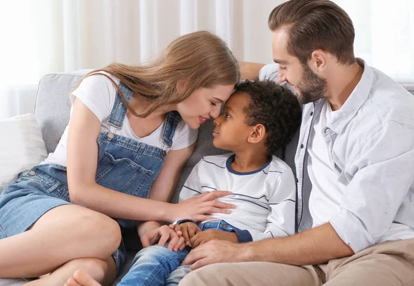 Pasangan bahagia dengan anak Afrika-Amerika yang diadopsi duduk di sofa di rumah — Stok Foto