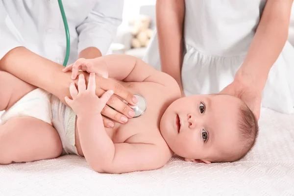 Læge undersøger baby med stetoskop hjemme - Stock-foto