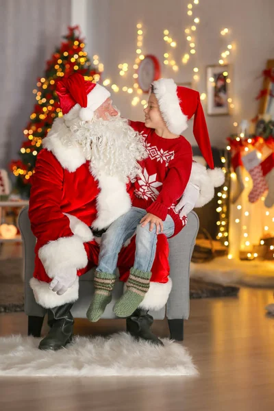 Gelukkig jongetje zittend op Santa's schoot in de kamer met mooie kerstversiering — Stockfoto