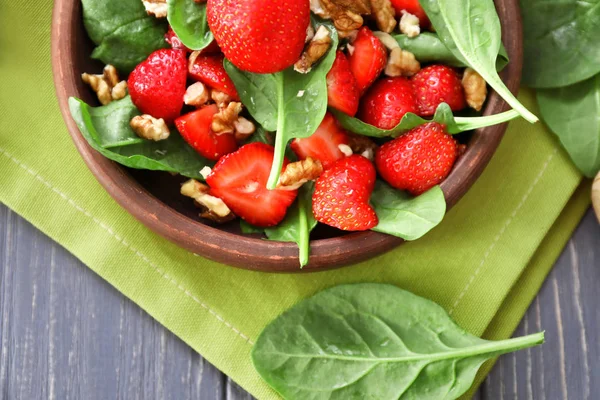 Teller Salat mit Spinat, Erdbeere und Walnüssen auf dem Tisch — Stockfoto
