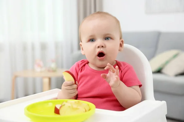 En liten baby som spiser eple innendørs – stockfoto