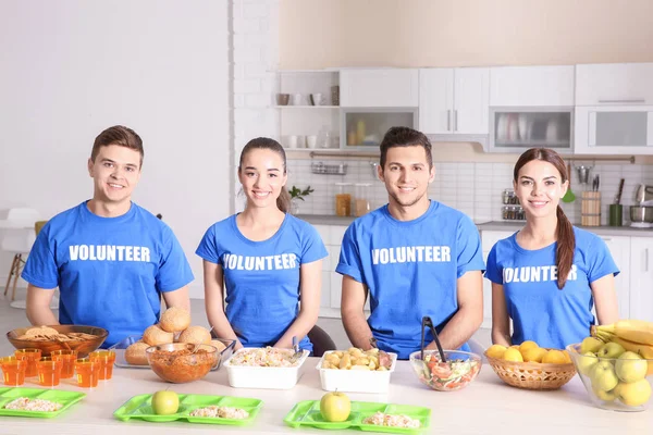 Equipo de adolescentes voluntarios listos para servir comida a personas sin hogar en la cocina — Foto de Stock