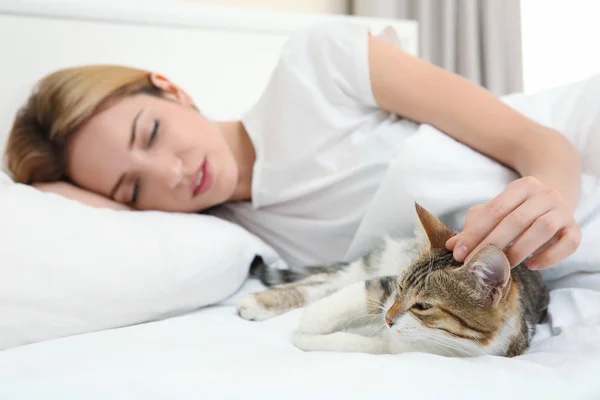 Mooie jongedame met kat liggend op bed thuis — Stockfoto