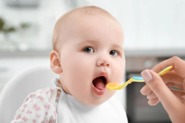 Madre alimentar al bebé con cuchara en la cocina —  Fotos de Stock