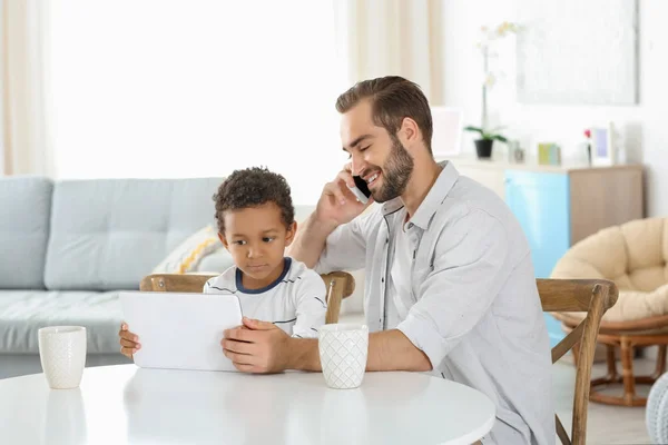 Pai feliz com adotivo menino afro-americano usando tablet computador na sala de estar — Fotografia de Stock