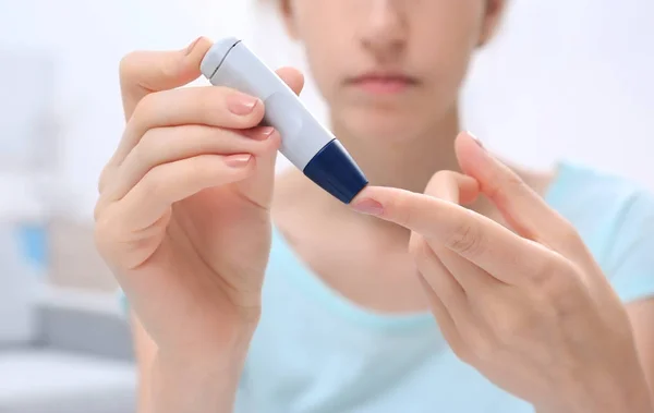 Woman taking blood sample with lancet pen at home — Stock Photo, Image