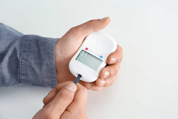 Menschenhände mit digitalem Glukometer auf weißem Hintergrund. Diabetes-Konzept — Stockfoto