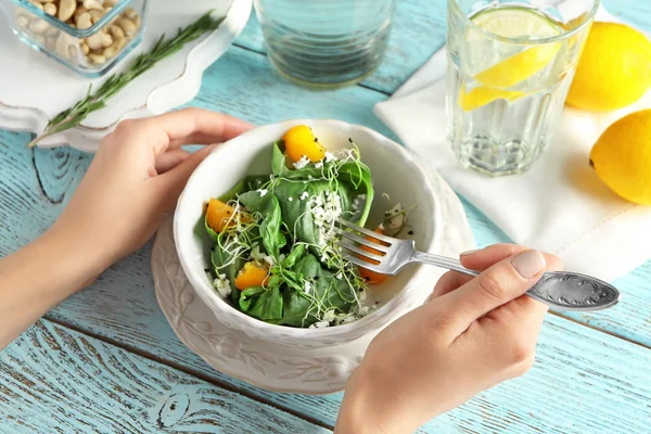 Mulher comendo salada de superalimento com tomate e espinafre à mesa — Fotografia de Stock