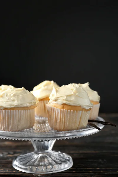 Dessert stå med god vanilj cupcakes på svart bakgrund — Stockfoto