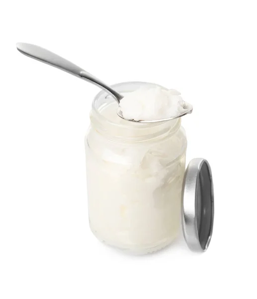 Colher e jarra com óleo de coco sobre fundo branco — Fotografia de Stock