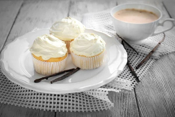 Cupcakes de baunilha saborosos e xícara de café na mesa — Fotografia de Stock