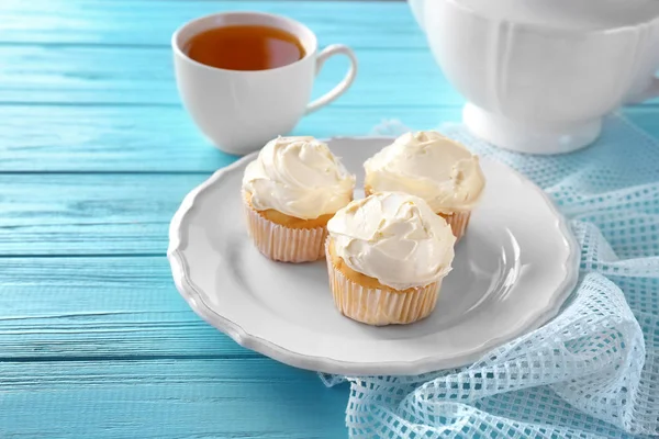 Plate with tasty vanilla cupcakes and cup of tea on table — Stock Photo, Image