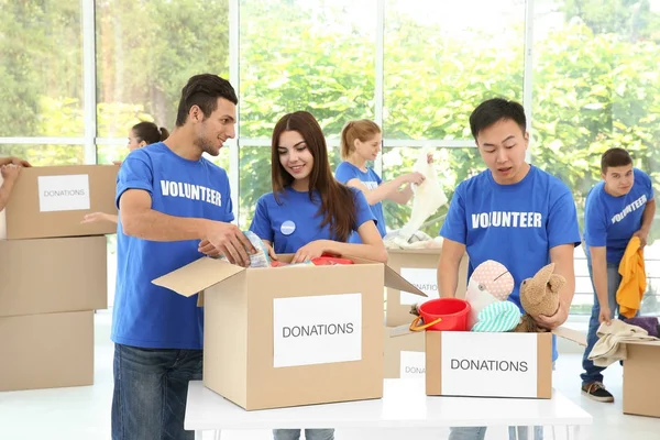 Команда подростков-волонтеров собирает пожертвования в картонных коробках в помещении — стоковое фото