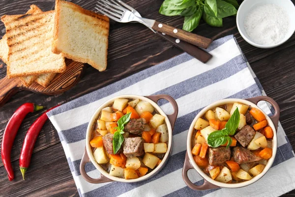 Casseroles with tasty meat and potatoes on table — Stock Photo, Image