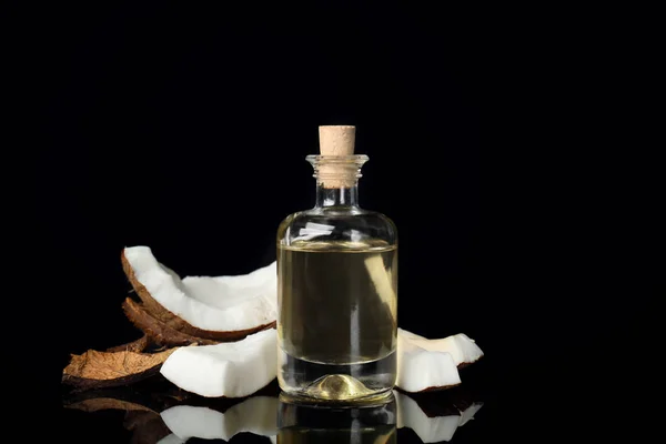 Bottiglia con olio di cocco fresco su sfondo nero — Foto Stock