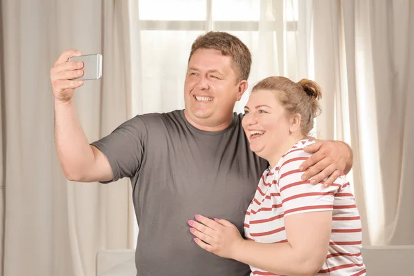 Overweight couple taking selfie at home — Stock Photo, Image