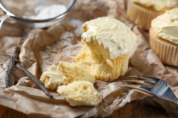 Tasty vanilla cupcake on parchment paper — Stock Photo, Image