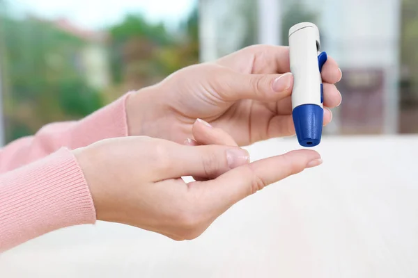 Woman taking blood sample with lancet pen — Stock Photo, Image