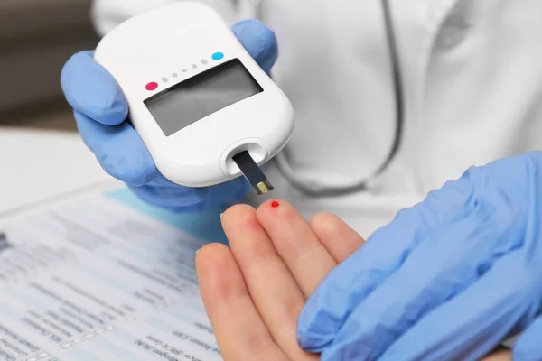 Úsekový laborant v latexové rukavice testování pacienta úroveň glukózy s digitální glukometr v nemocnici — Stock fotografie