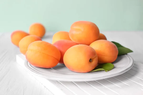 Plate with fresh apricots on wooden table — Stock Photo, Image