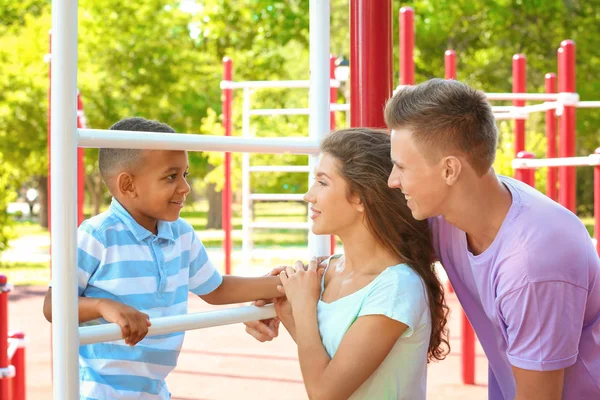 Junge Familie mit adoptiertem afrikanisch-amerikanischem Jungen auf dem Sportplatz — Stockfoto