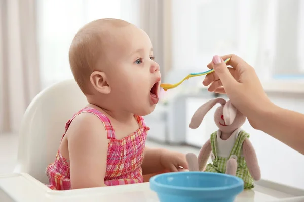 Madre alimentando al bebé con cuchara en el interior — Foto de Stock