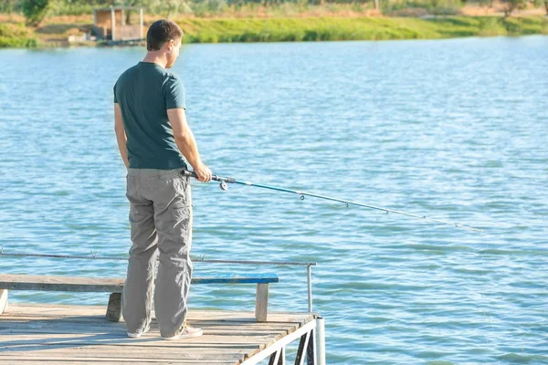 Hombre pescando desde el muelle en el río — Foto de Stock