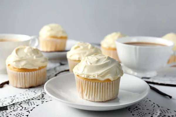 Tasty vanilla cupcakes and cups on table — Stock Photo, Image
