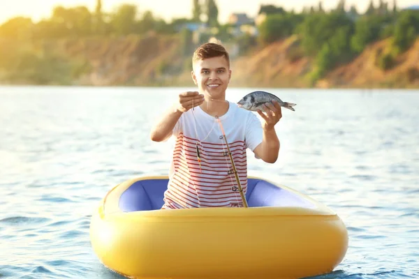Junger Mann fischt von Schlauchboot auf Fluss — Stockfoto