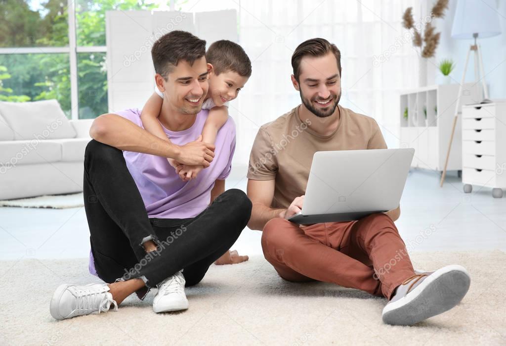 Male gay couple with foster son sitting on floor. Adoption concept