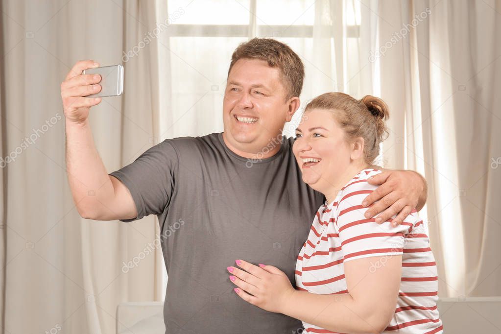 Overweight couple taking selfie at home