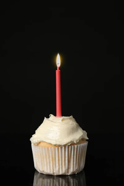 Sabroso cupcake de vainilla con vela sobre fondo negro — Foto de Stock