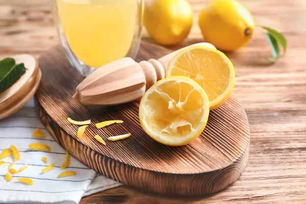 Свежие лимоны и соковыжималка на деревянном столе — стоковое фото