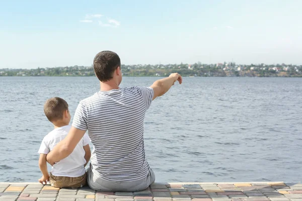 Отец и сын сидят на пирсе у реки — стоковое фото