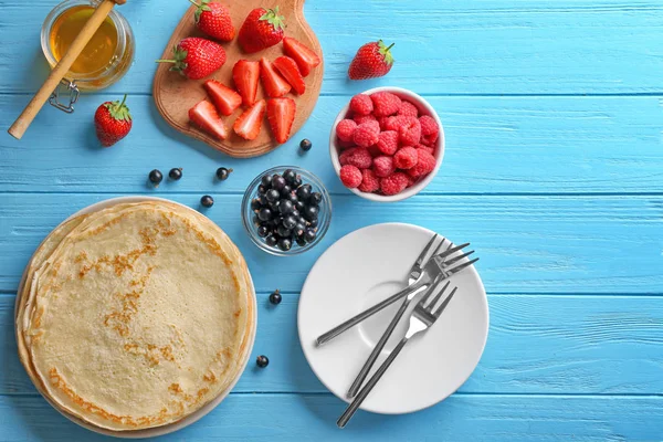 Composition avec de fines crêpes, du miel et des baies sur table en bois bleu — Photo