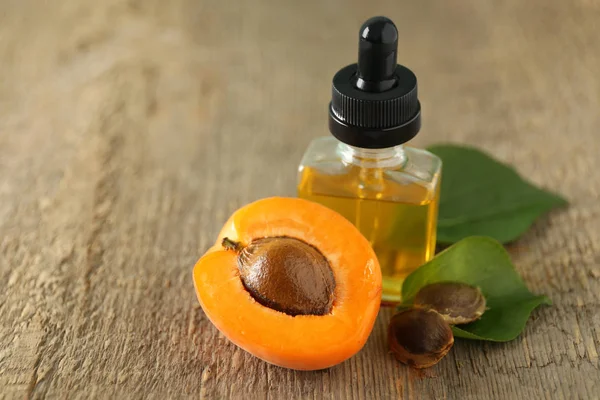 Bottle of apricot oil with fresh fruit on wooden table — Stock Photo, Image