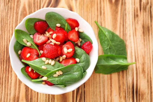 Teller Salat mit Spinat, Erdbeere und Pinienkernen auf dem Tisch — Stockfoto