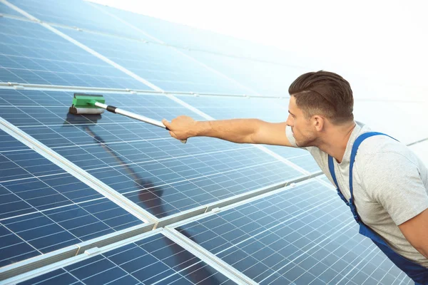 Young worker washing solar panels after installation outdoors — Stock Photo, Image