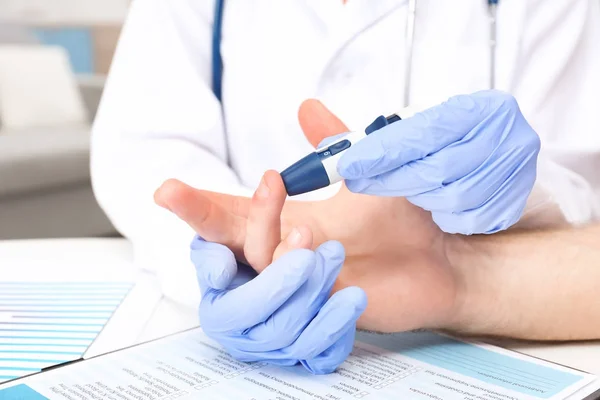 Доктор в латексных перчатках берет образец крови пациента с помощью ручки Ланцета. Концепция диабета — стоковое фото