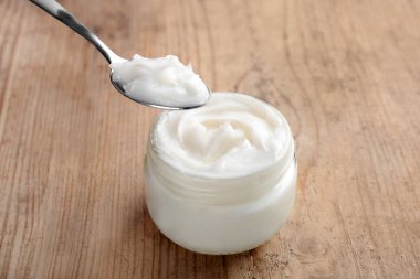 Kaşık ve ahşap masa üzerine Hindistan cevizi yağı kavanoz