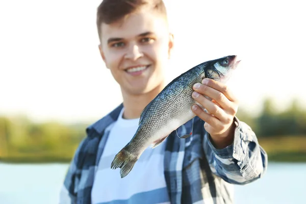 挽きたてを保持している若い男は、魚をキャッチ — ストック写真