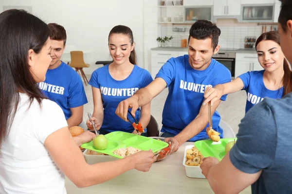 Adolescentes voluntarios sirviendo comida para personas sin hogar en interiores —  Fotos de Stock