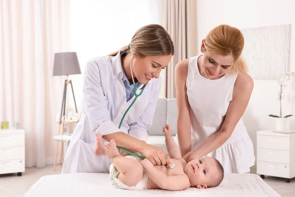 Doctor examining baby with stethoscope at home — Stock Photo, Image