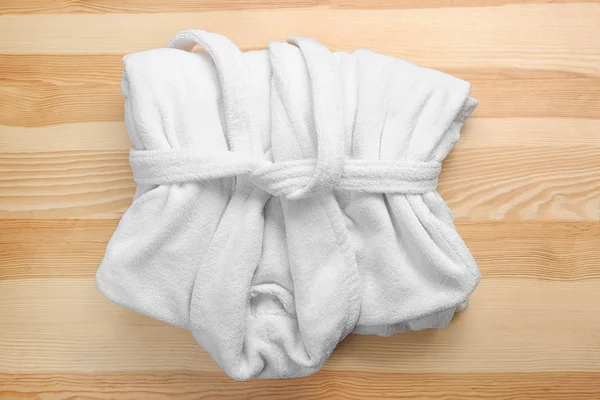 Folded white bathrobe on wooden background — Stock Photo, Image