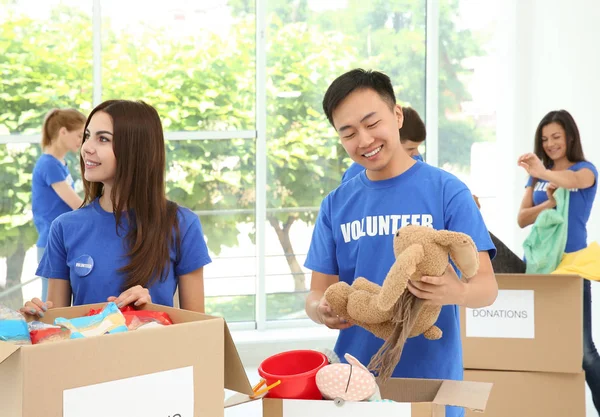 Team of teen volunteers collecting donations in cardboard boxes indoors