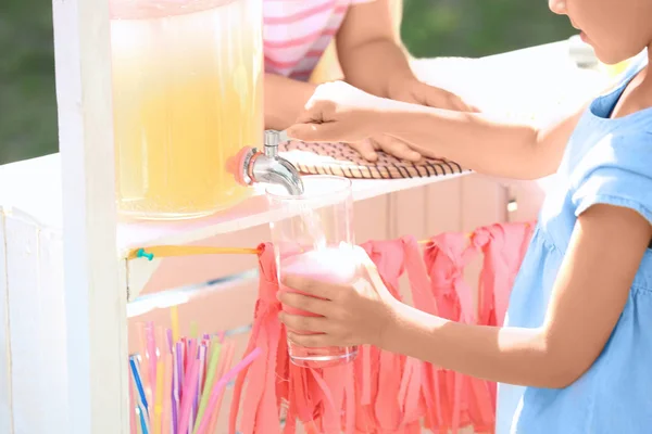 Ragazzina versando limonata dal barattolo con rubinetto — Foto Stock