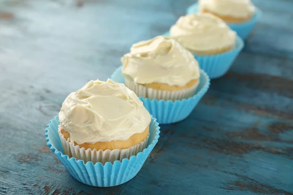 Chutné vanilkové cupcakes na dřevěný stůl — Stock fotografie