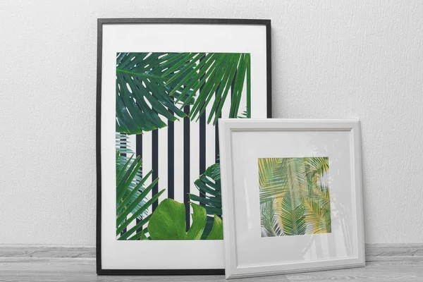 Картины в рамке тропических листьев на фоне белой стены — стоковое фото