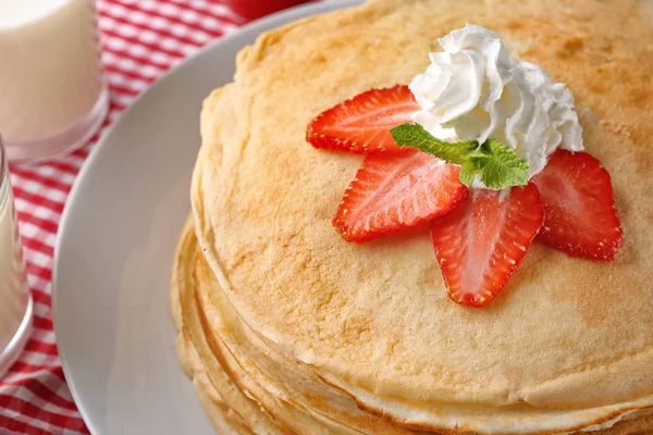 Setumpuk pancake tipis disajikan dengan stroberi dan krim kocok di piring putih — Stok Foto