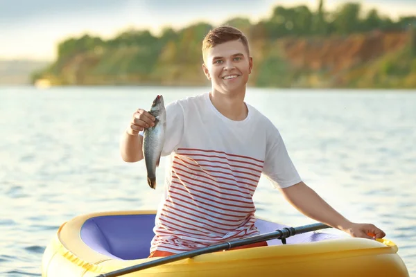 Homem novo que pesca do barco inflável no rio — Fotografia de Stock